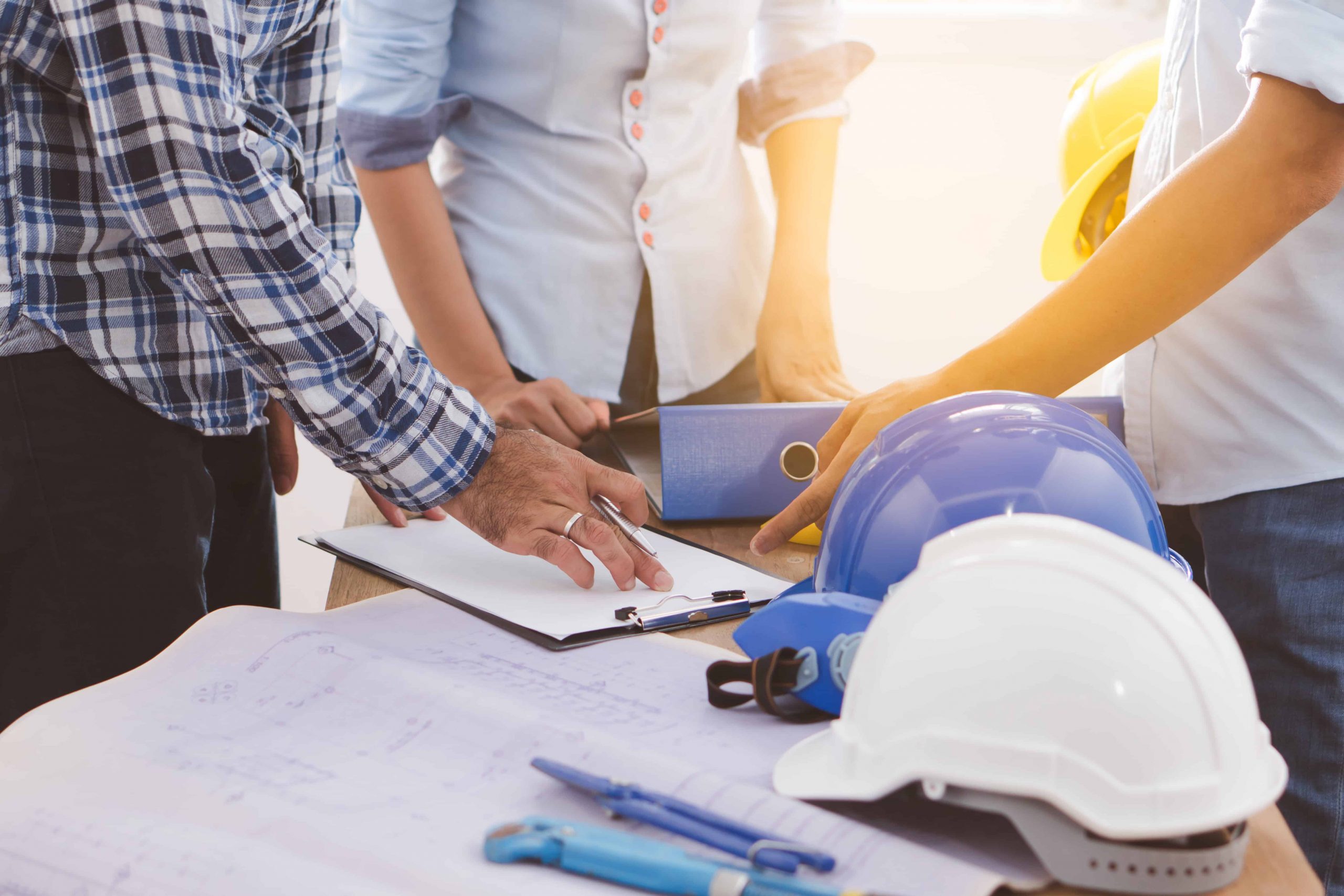 Three men standing around hard hats.